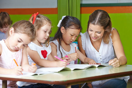 kids at daycare writing with help from teacher