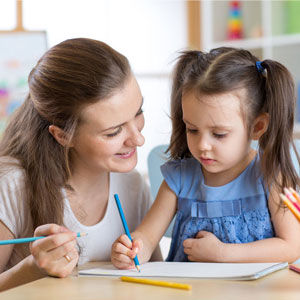 Child drawing with daycare teacher